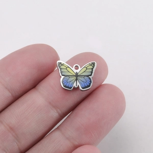 Detailed close-up of a color-printed butterfly pendant held by hand for size perspective
