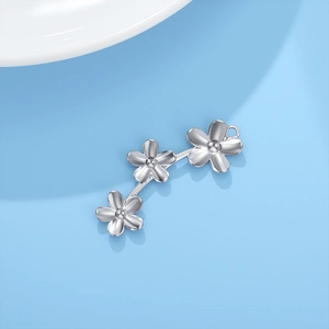 Gros plan sur un pendentif à trois fleurs en argent avec finition métallique polie