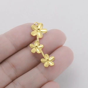 Gros plan sur trois pendentifs fleurs dorées connectés pour la création de bijoux
