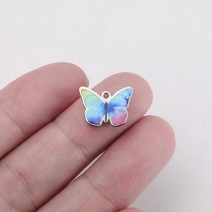 Detail showing the size of colorful gradient butterfly pendant held by hand for DIY jewelry