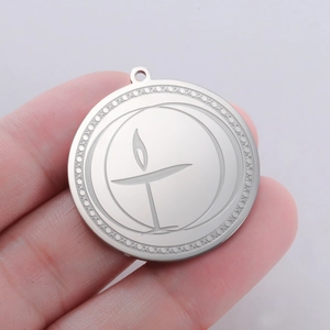 Detailed macro of a stainless steel flaming grail pendant held between fingers