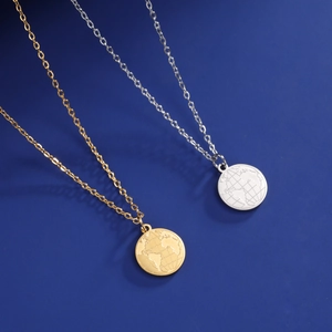 Detail of world map etched stainless steel round pendants in gold and silver finishes