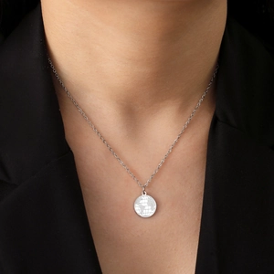 Detail of world map engraved stainless steel pendant necklace on a black suit blazer