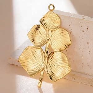 Macro detail of golden stainless steel leaf charms with intricate vein texture and top rings