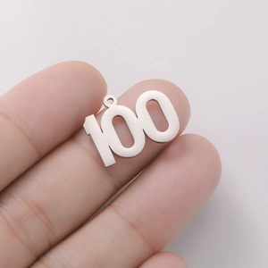 Polished stainless steel number 100 charm pendant held by hand for scale and size