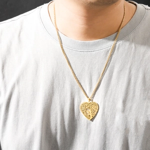 Golden heart pendant necklace with intricate tree of life design worn by a female model