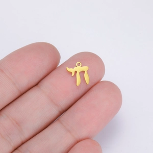 Detailed close-up of golden stainless steel Hebrew Chai symbol pendant on a fingertip