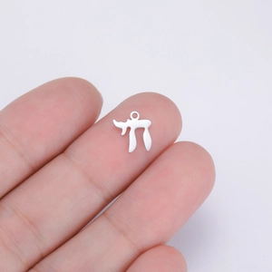 Close-up of silver steel Chai symbol pendant held between fingers showing tiny size