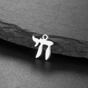 Macro shot of silver Chai symbol pendant representing life on a black stone surface