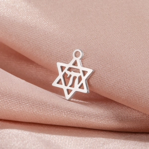 Gros plan du pendentif hexagramme argenté avec symbole hébreu Chai sur soie rose