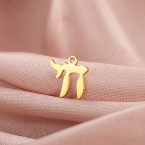Polished 18K gold Chai symbol pendant on soft pink satin fabric background