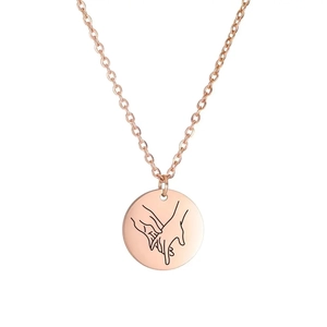 Close-up of rose gold necklace with a round pendant featuring a pinky swear engraving