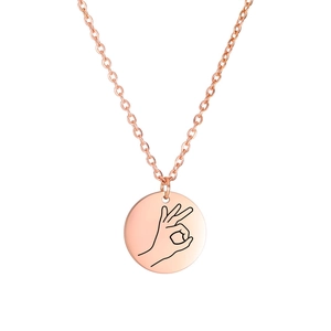 Macro detail of rose gold stainless steel round necklace with minimalist OK hand gesture engraving