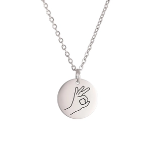 Detailed view of polished silver round pendant necklace with minimalist OK gesture engraving