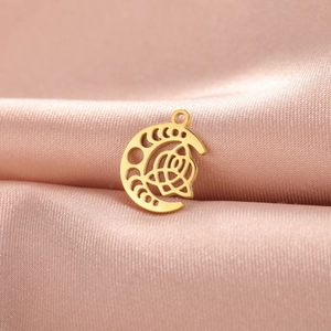 Close-up of 18K gold plated moon and rose pendant on soft pink satin fabric