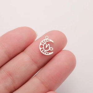 Detail view of silver hollow moon pendant with letter M on hand for scale