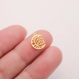 Detail of a small 18K gold crescent moon charm with Celtic knot pattern on a fingertip