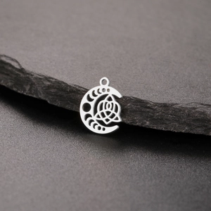Silver crescent moon pendant with intricate Celtic knot engraving on a dark stone surface