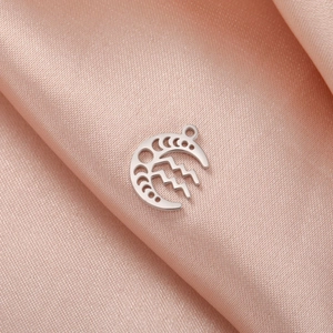 Detailed view of silver crescent moon Aquarius pendant on soft pink silk background