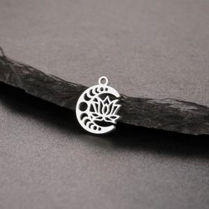 Polished silver lotus and crescent moon phase pendant on dark natural stone background