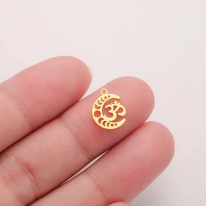 Detailed view of a gold Om crescent moon pendant held by fingers to show small size