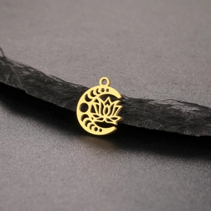Detailed close-up of golden moon and lotus pendant on a grey textured slate background
