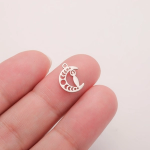 Macro detail of silver crescent moon pendant showing hollow design held by fingers