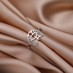 Détail macro d'une bague en acier avec découpes phases de lune sur fond satiné