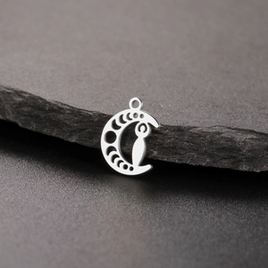 Detailed shot of silver moon phase goddess pendant on dark slate stone background