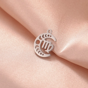 Macro shot of silver Virgo zodiac moon phase pendant on elegant pink silk fabric