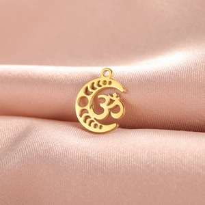 Detailed view of a gold moon pendant with an Om symbol on smooth pink silk fabric