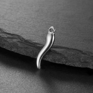Macro detail of high-polish silver chili pepper charm on a natural slate stone surface