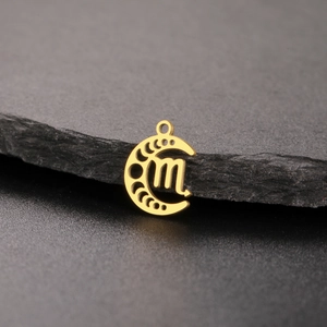 Close-up of golden moon phase pendant with engraved zodiac symbol on dark rock surface