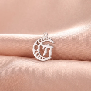 Close-up of polished silver moon phase pendant with Celtic knot on pink silk fabric