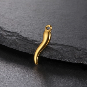 Polished gold chili pepper pendant charm for jewelry on a textured stone background