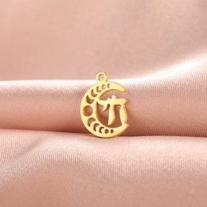Golden moon pendant with Hebrew Chai symbol cutout on elegant pink silk fabric