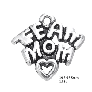Macro shot of silver heart-shaped TEAM MOM pendant with sports charms texture