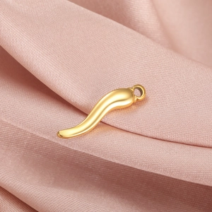 Polished gold chili pendant accessory on soft pink silk fabric with a top hanging loop