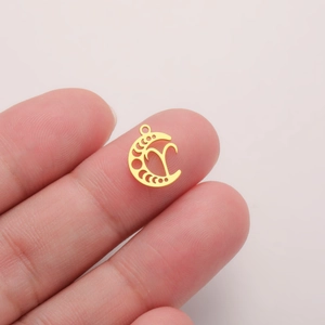 Macro shot of 18K gold crescent moon Aries zodiac charm held to show miniature scale