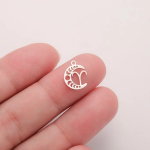 Detailed close-up of a hollow crescent moon zodiac pendant held between fingers