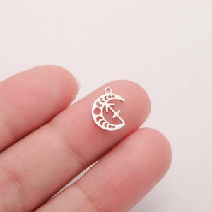 Macro detail of a small silver stainless steel crescent moon pendant with Sagittarius symbol