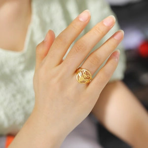 Detailansicht eines goldenen Rings mit ausgeschnittenem Cartoon-Motiv am Finger