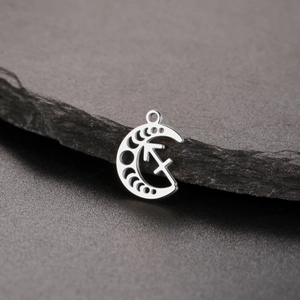Detailed macro shot of silver crescent moon Sagittarius zodiac pendant on a dark stone
