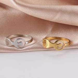 Gros plan de bagues punk argent et or avec motifs spirales sur satin champagne