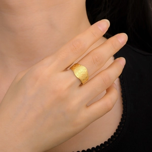 Close-up of a wide gold-plated stainless steel ring with an embossed Tree of Life pattern