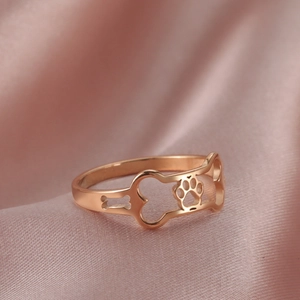 Close-up of rose gold hollow ring featuring bone and dog paw prints on pink silk