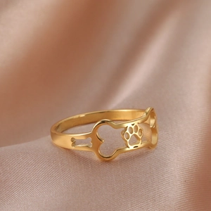 Detailed view of golden dog paw and bone cutout patterns on a stainless steel ring