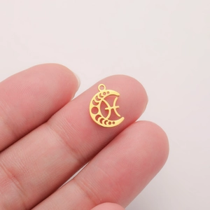 Detailed view of a gold crescent moon Pisces pendant held on a fingertip for size reference