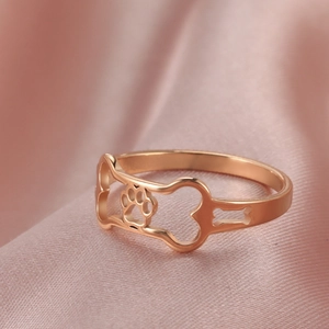 Detailed macro view of rose gold dog paw and bone cutouts on a polished stainless steel ring