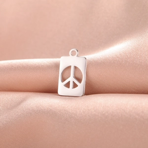 Detailed view of silver peace sign pendant on a soft champagne silk fabric background